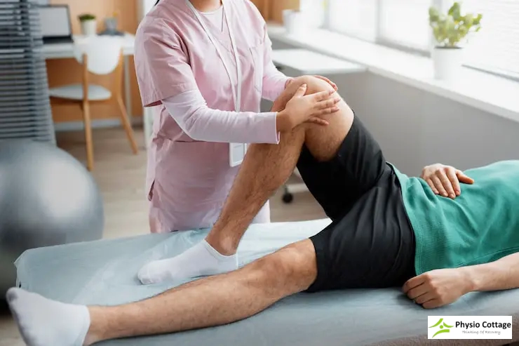 A female physiotherapist is examining and gently moving knee of a male patient.