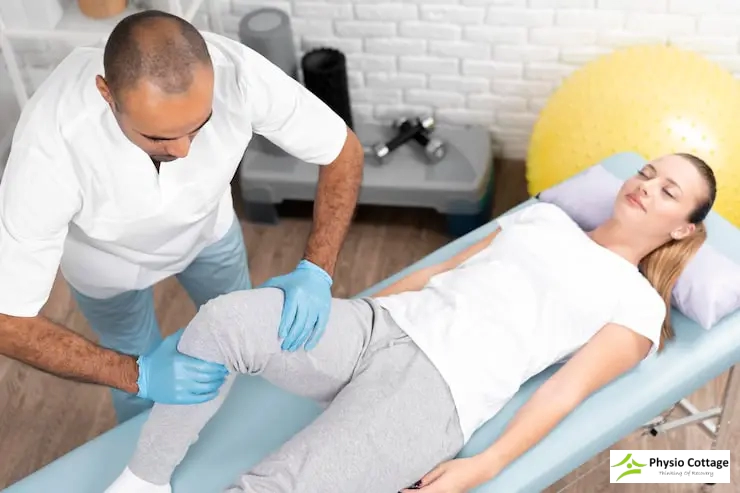 A male physiotherapist moves the knee of a female patient.