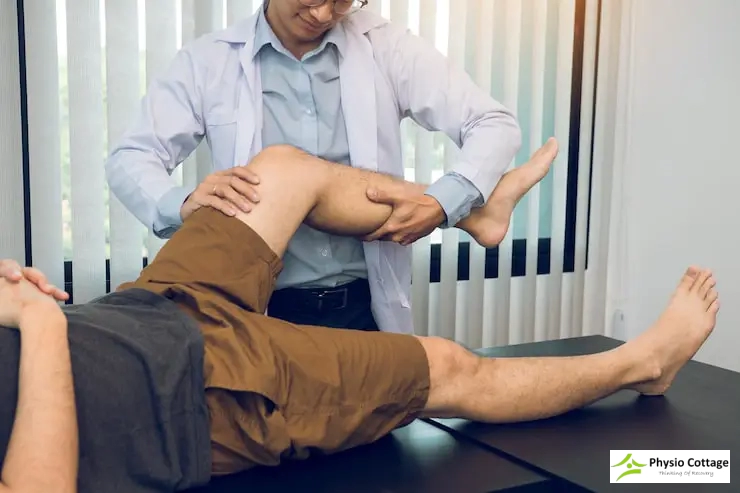A male physiotherapist performs a passive on a male patient's knee and leg.