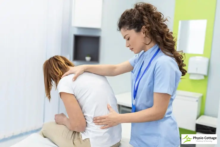 A female physiotherapist applies therapy techniques to back of a patient.