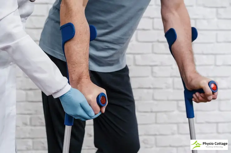 A close-up of a person's arms and hands using a pair of blue crutches.