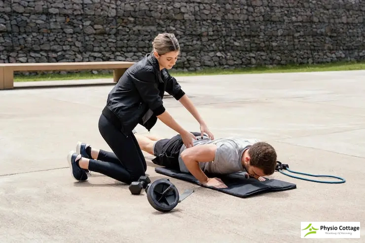 A female physiotherapist is helping a male client perform a push-up exercise on a mat.