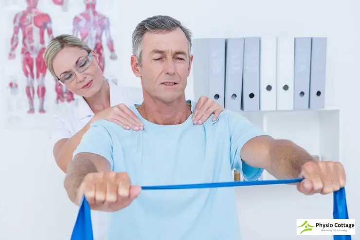 A patient performs a shoulder exercise with a blue resistance band.